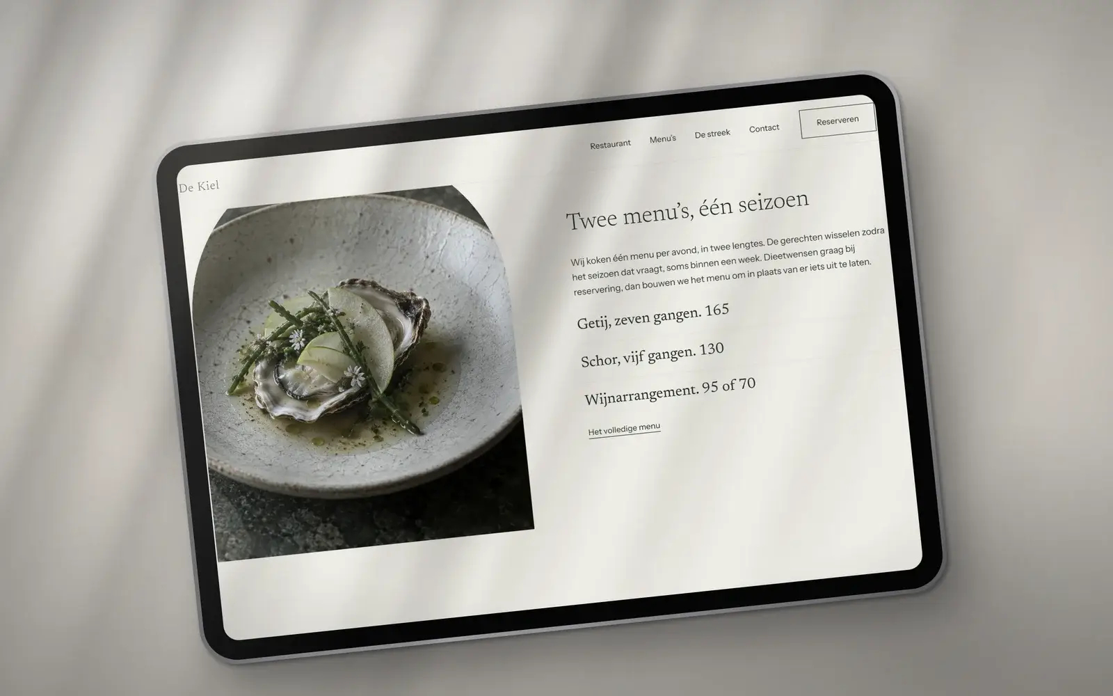 De twee menu’s van De Kiel op een tablet, naast een oester in een boogvormige uitsnede