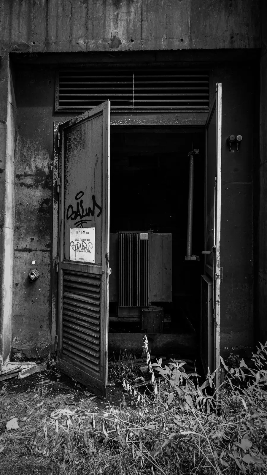 Openstaande stalen deur van een verlaten transformatorhuis