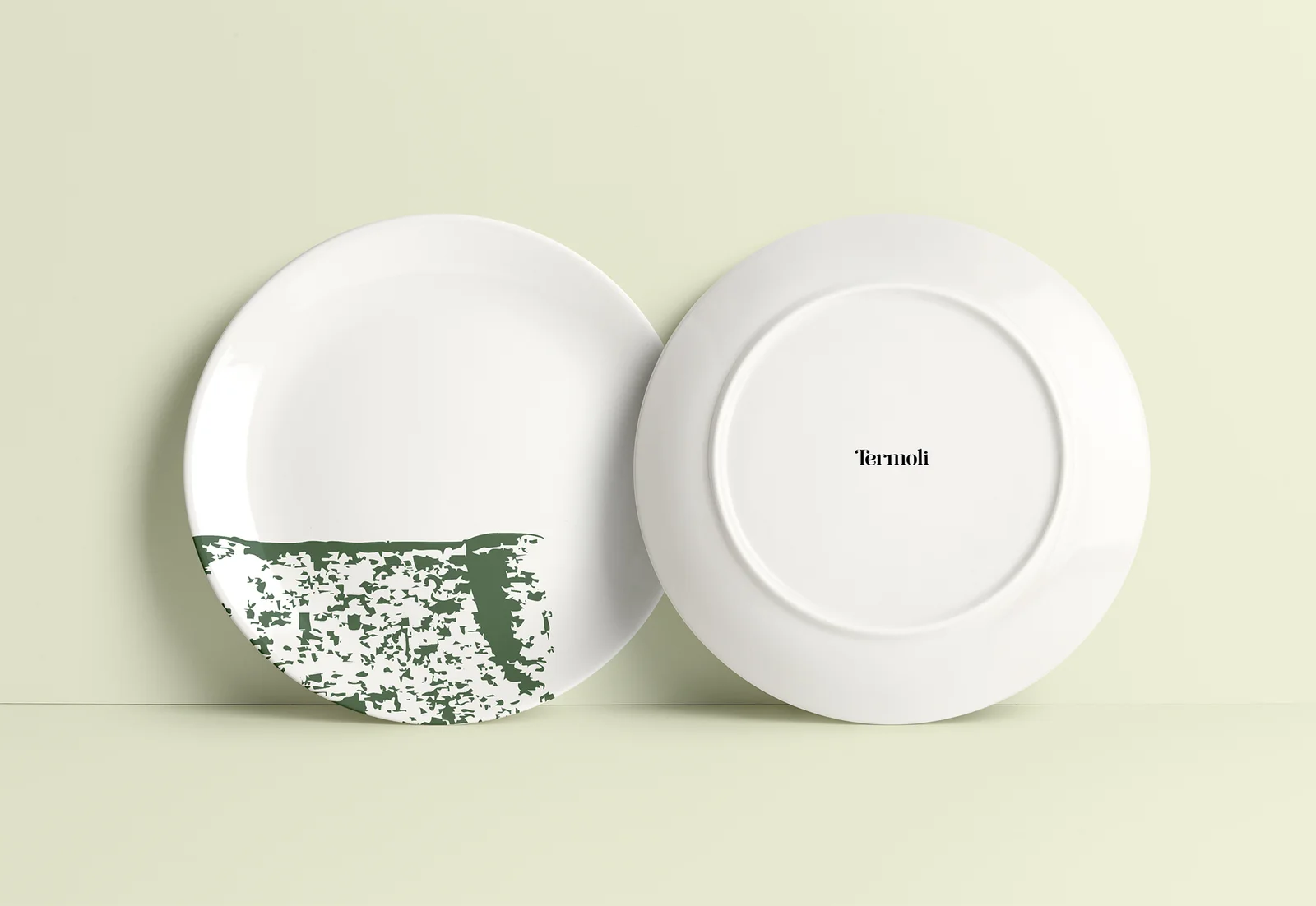 Twee witte borden van Termoli, één met een groen patroon en één met het woordmerk op de achterkant