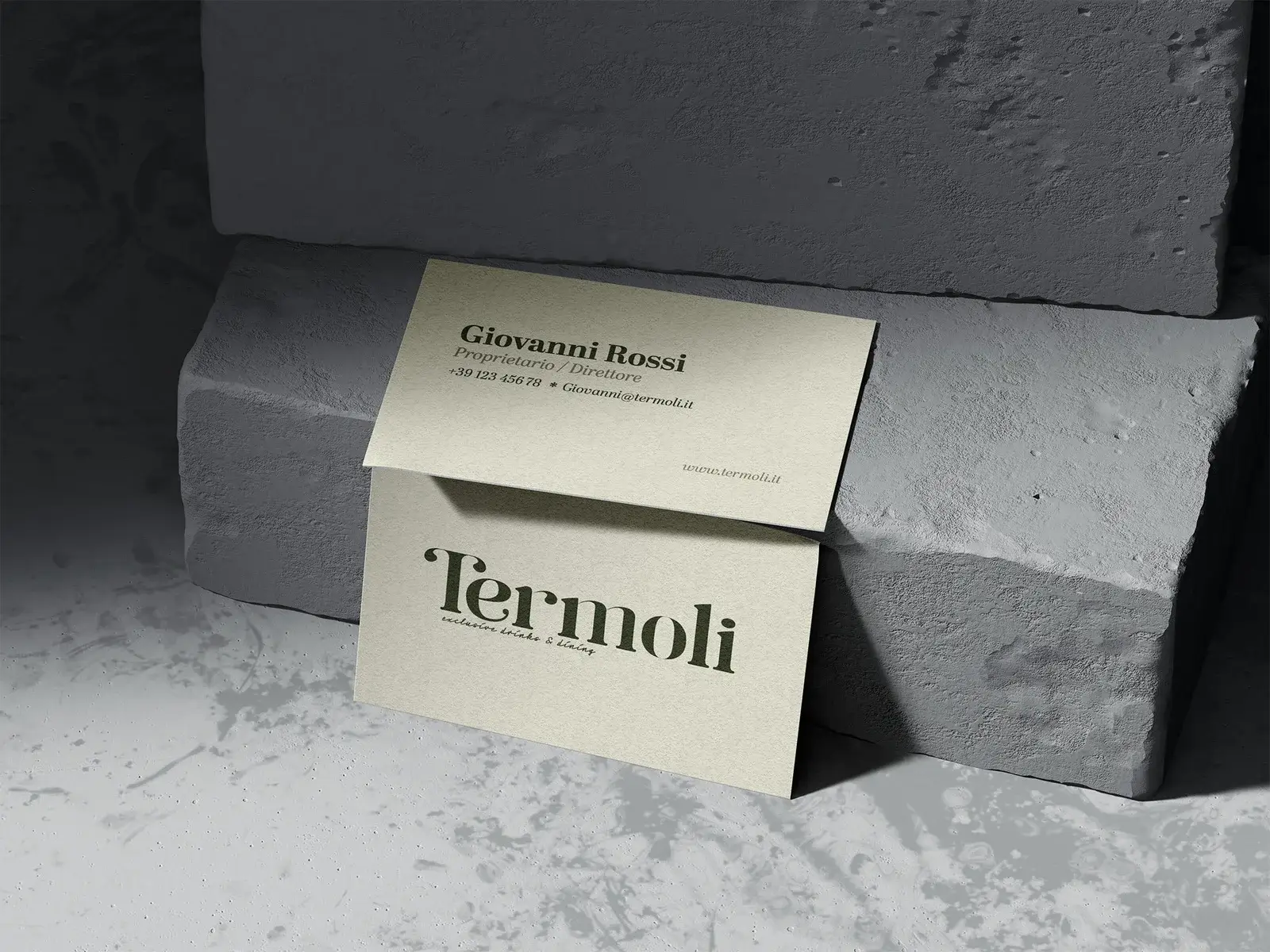 Visitekaartjes van Termoli met het donkergroene woordmerk op gebroken wit papier, tegen grijze steen